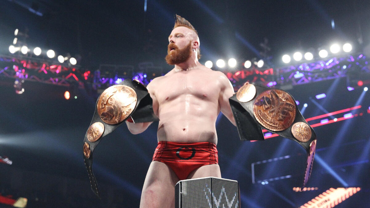 After snatching the titles from the defeated champions, Sheamus celebrates the victory with both prizes.