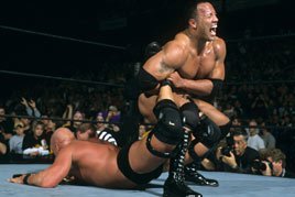 The Rock puts Steve Austin in the Sharpshooter.